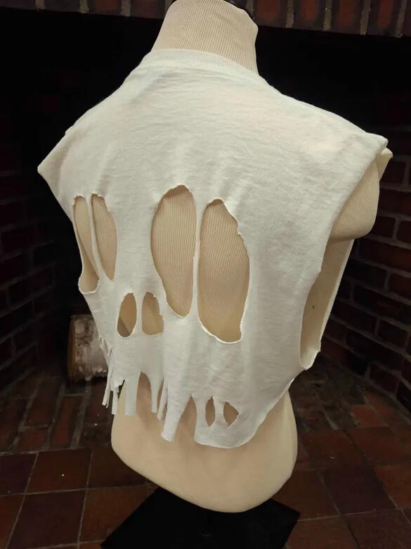 skull crop back a white tee shirt cut sleeveless and cropped, with additional holes cut in the back to resemble the shape of a skull, with the holes making the mouth partially extending to the bottom of the shirt making a fray.