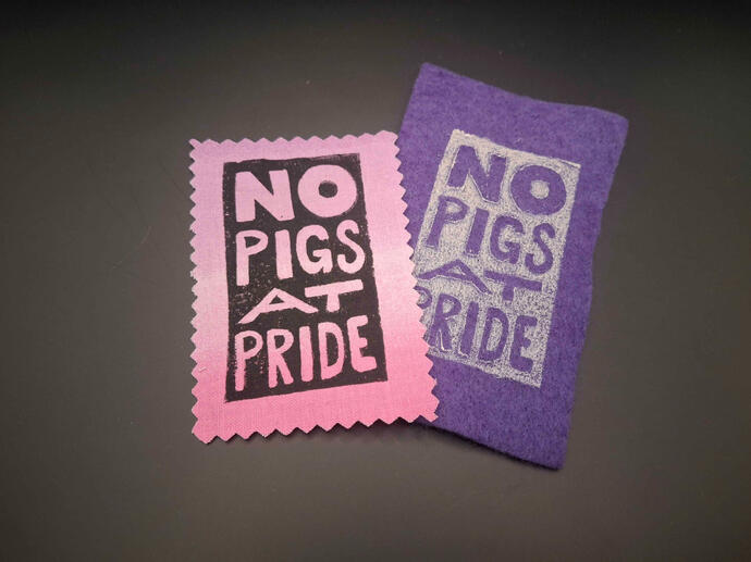Block printed patches of the words "no pigs at pride" stacked on each other on a solid background.