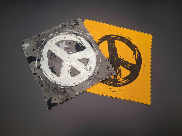 Block printed patches of a texturally distressed peace sign.