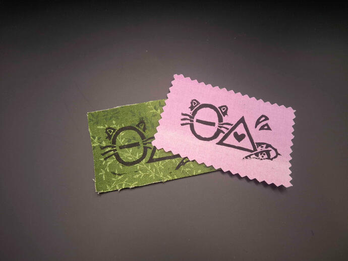 Block printed patches of theta delta (ΘΔ) with embellishments making the theta raccoon-like and delta lizard-like.